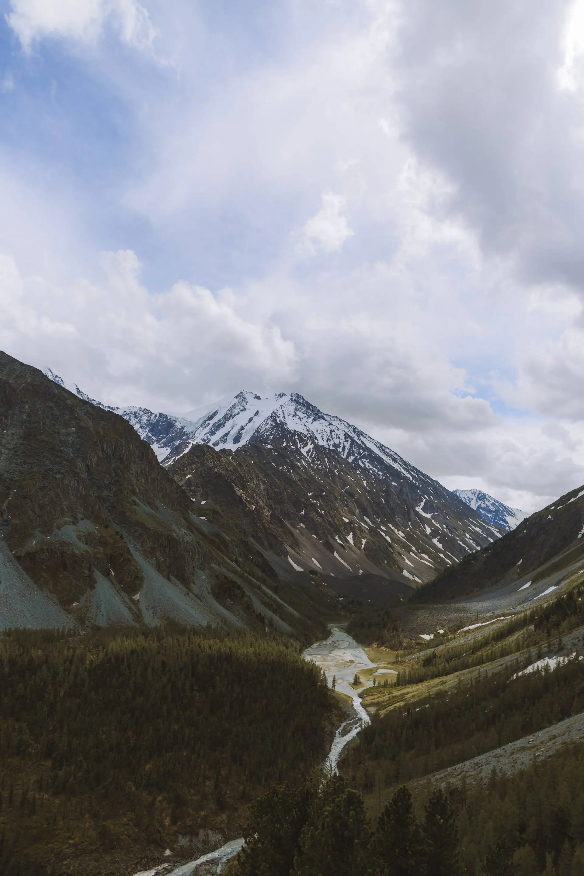 A mountain valley with a river winding toward snow-capped peaks.